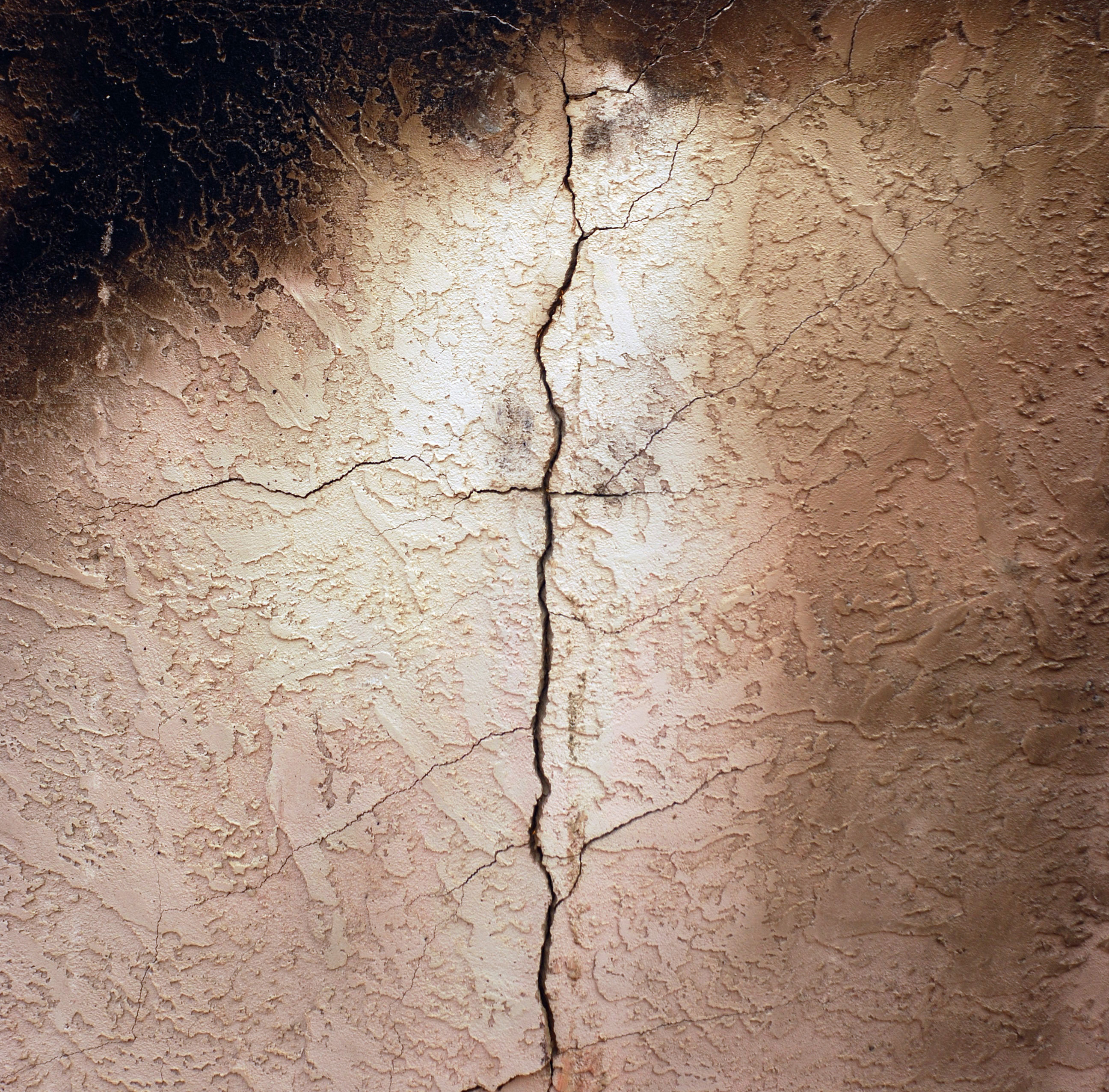 A plaster wall damaged by fire with a crack running up the middle.
